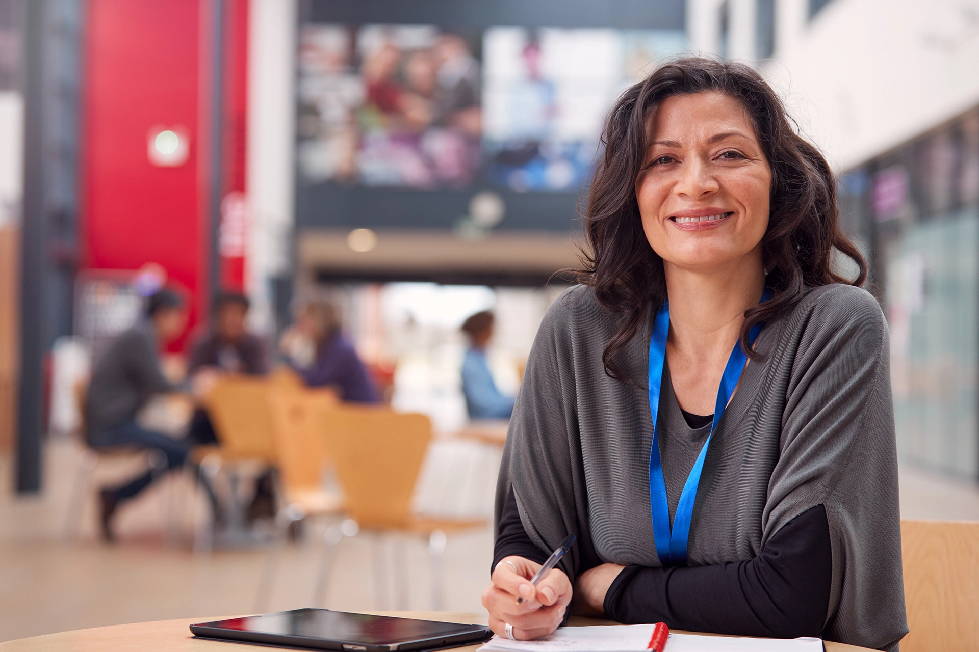 Female teacher wearing blue lanyard and smiling directly at camera.
