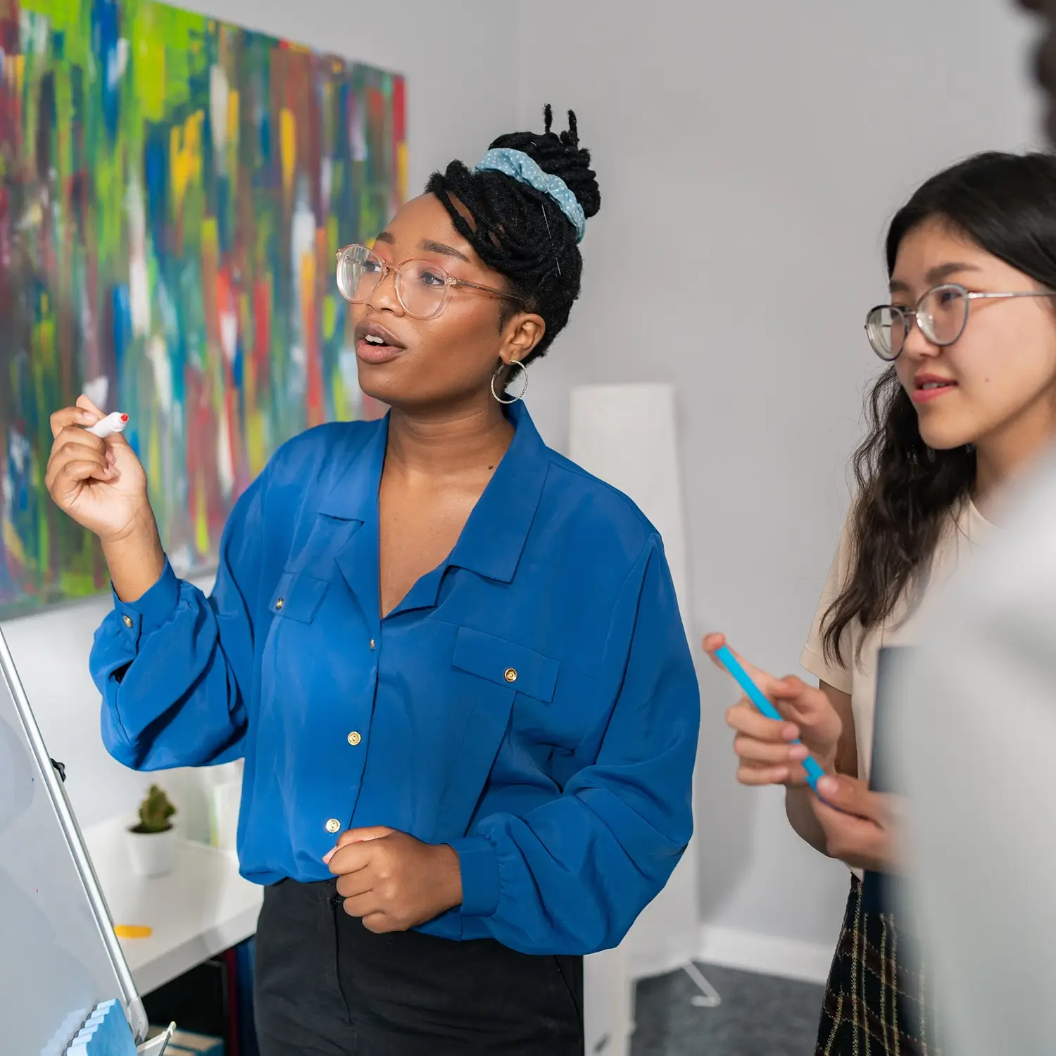 Two women looking at white board during teacher meeting.